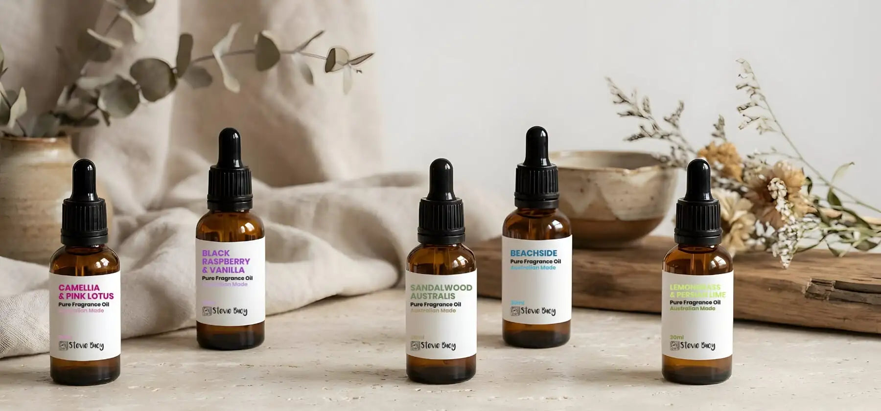 Five amber glass bottles with black dropper caps and white labels, each displaying a different fragrance scent.