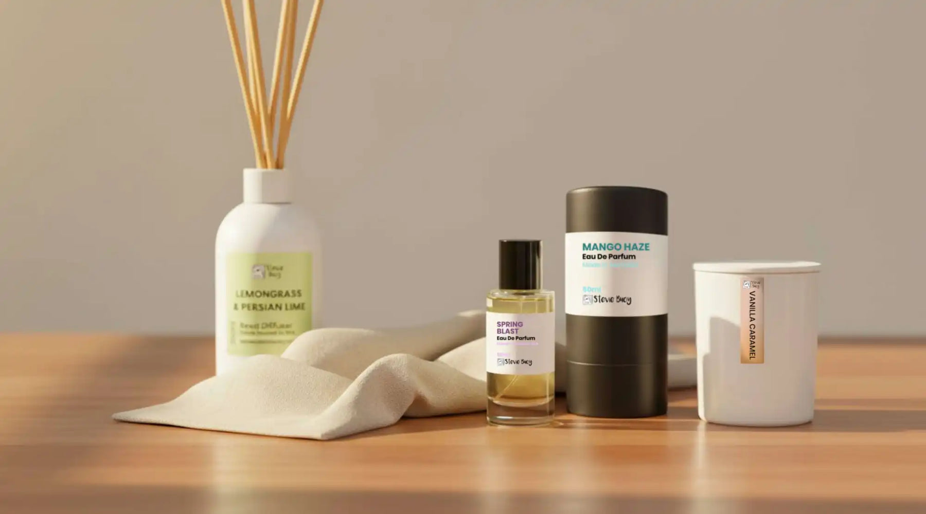 A collection of home fragrance and personal scent products, including a reed diffuser, a bottle of perfume, a cylindrical perfume case, and a scented candle.