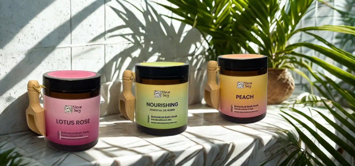 Three amber glass jars with colorful labels and lids, containing different scented body care products.